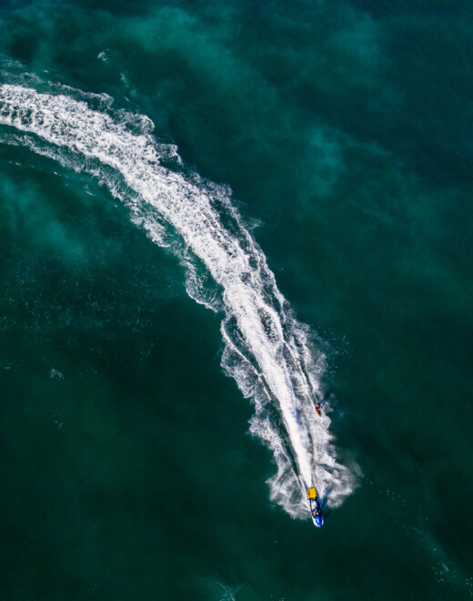 Aerial shot of a person jet skiing in bright green seawater